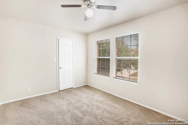 an empty room with a window and a ceiling fan
