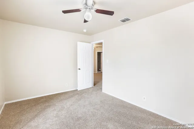an empty room with a chandelier fan and windows