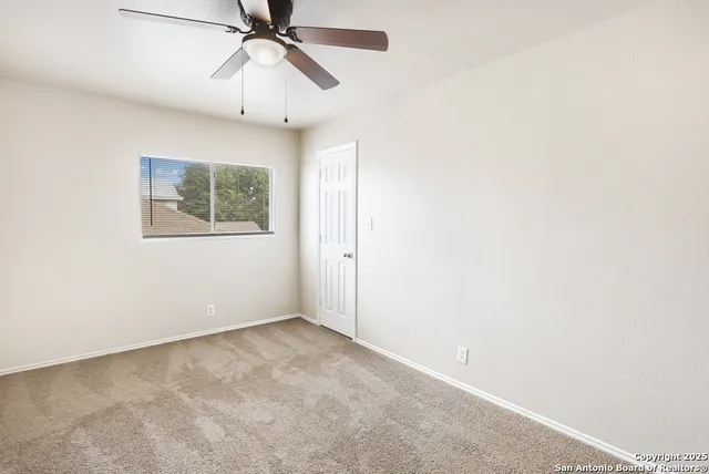 an empty room with a ceiling fan and a window
