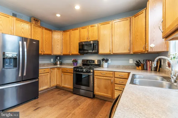 a kitchen with stainless steel appliances granite countertop a stove a sink dishwasher a refrigerator and cabinets with wooden floor