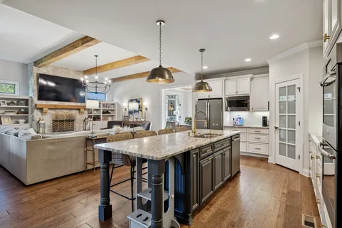 a kitchen with granite countertop stainless steel appliances a dining table chairs and sink