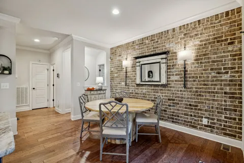 a kitchen with stainless steel appliances granite countertop a stove top oven a sink dishwasher a dining table and chairs with wooden floor