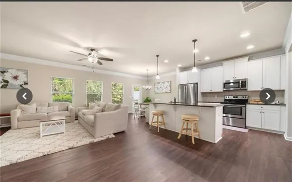 a large open kitchen with a refrigerator a stove a sink a dining table and chairs with wooden floor