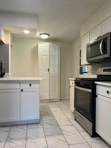 a kitchen with white cabinets and appliances