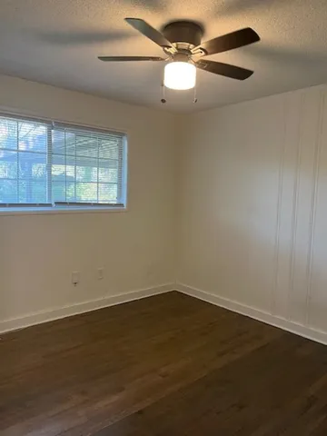 en empty room with wooden floor fan and window