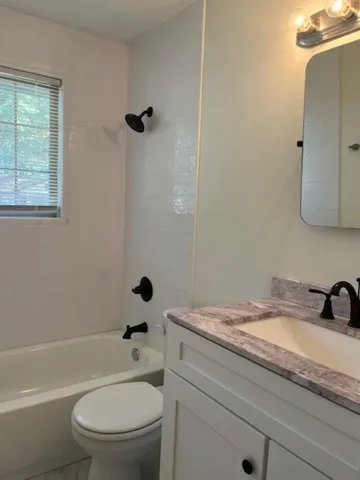 a bathroom with a granite countertop toilet a sink a mirror and shower