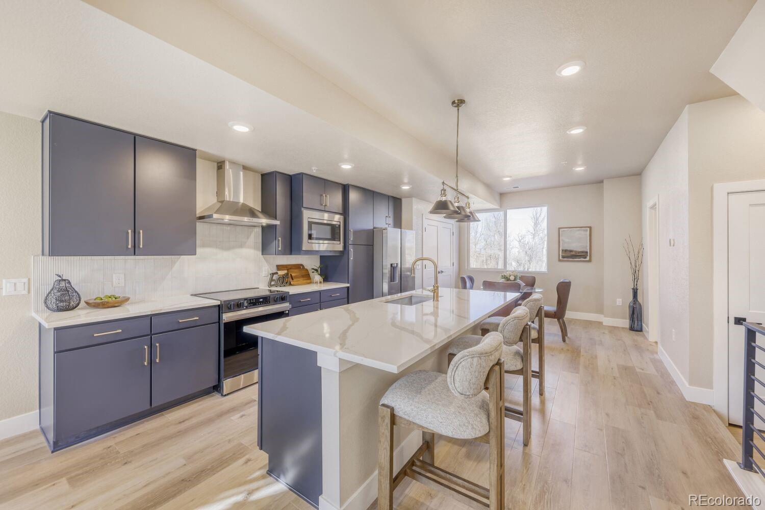9195 Pierce Street, Unit 7 Westminster, CO 80021 - Photo 12 of 25 a kitchen with stainless steel appliances kitchen island granite countertop a stove a sink a refrigerator and white cabinets with wooden floor