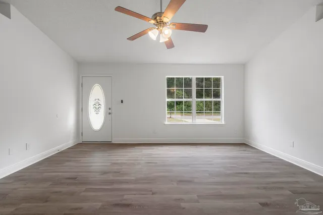 an empty room with window and ceiling fan