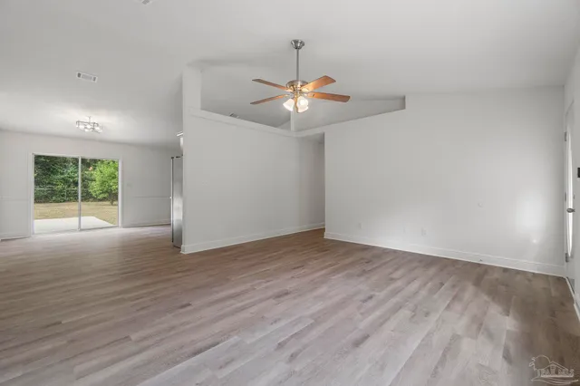 a view of an empty room with window and wooden floor