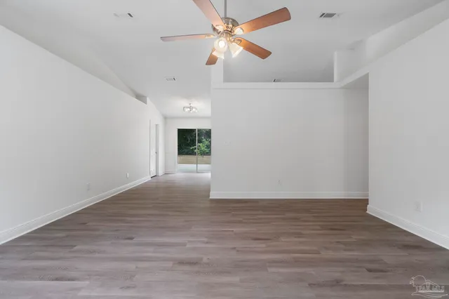a view of an empty room with window and a ceiling fan