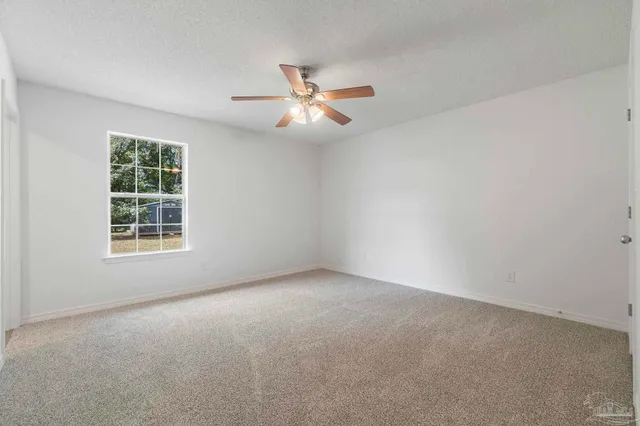an empty room with a window and a fan