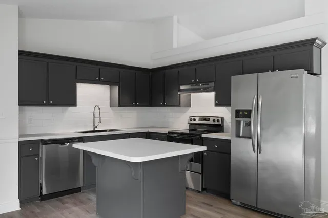 a kitchen with stainless steel appliances a refrigerator a sink a stove a microwave and cabinets