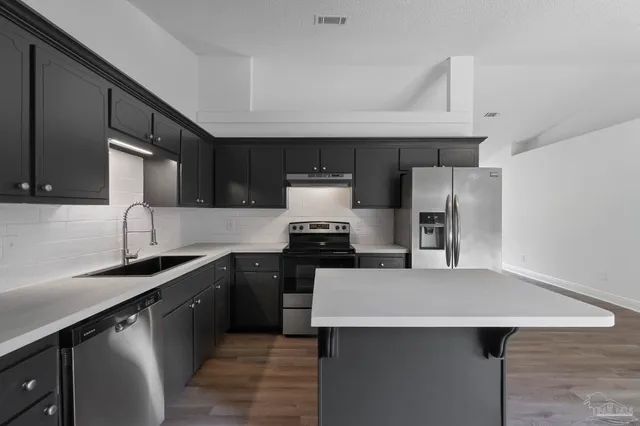 a kitchen with stainless steel appliances a sink dishwasher stove refrigerator and cabinets