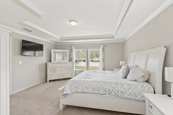 a bedroom with a bed a tv and wooden floor