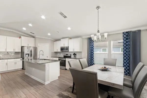 a kitchen with stainless steel appliances kitchen island granite countertop a table chairs and a refrigerator
