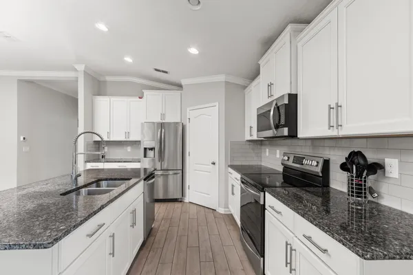 a kitchen with stainless steel appliances granite countertop a sink stove microwave and refrigerator