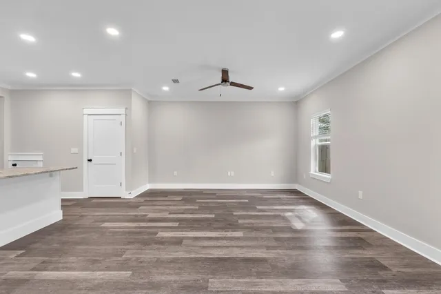a view of an empty room with wooden floor and a window