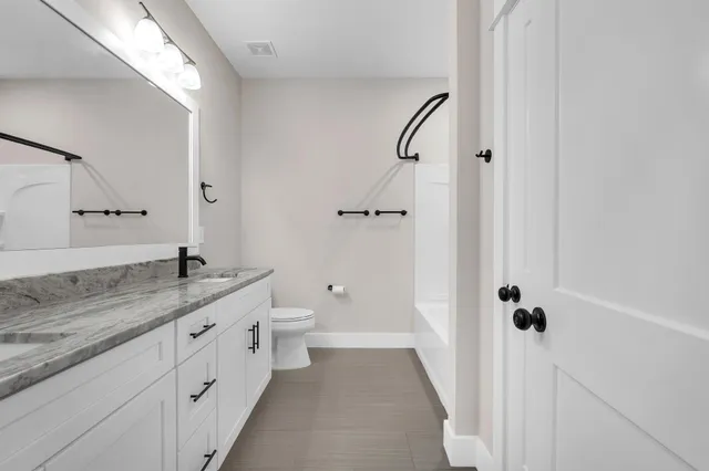 a bathroom with a granite countertop sink a toilet and a mirror