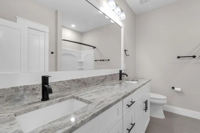 a bathroom with a granite countertop sink a toilet and a mirror