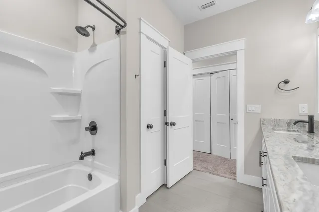 a bathroom with a tub sink vanity and shower