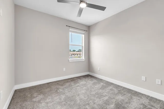 an empty room with a ceiling fan and window
