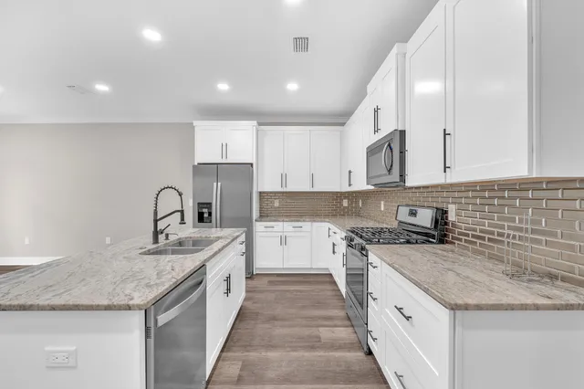 a kitchen with granite countertop sink stainless steel appliances and white cabinets
