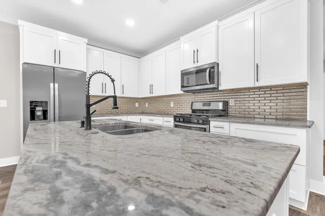 a kitchen with stainless steel appliances granite countertop a stove a sink and a microwave