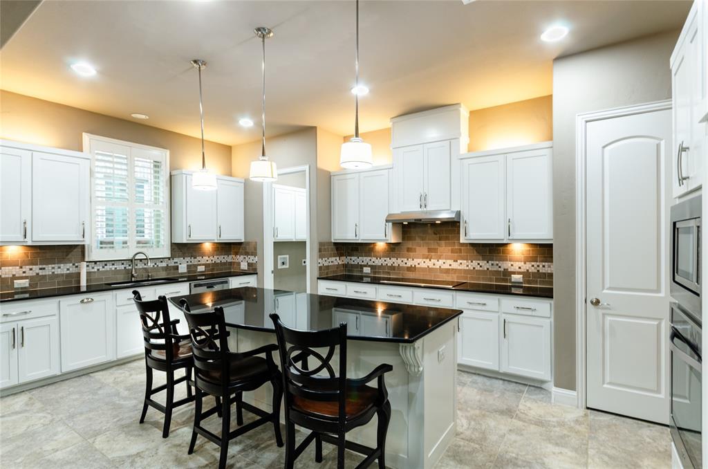 1863 Audubon Pond Way Allen, TX 75013 - Photo 5 of 40 a kitchen with stainless steel appliances granite countertop wooden floor sink stove and white cabinets