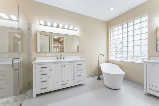 a spacious bathroom with a double vanity sink a large mirror and a bathtub