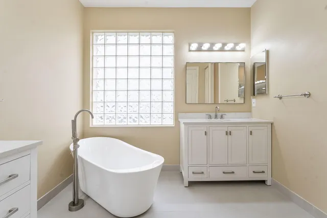 a bathroom with a double vanity sink a mirror and a bathtub