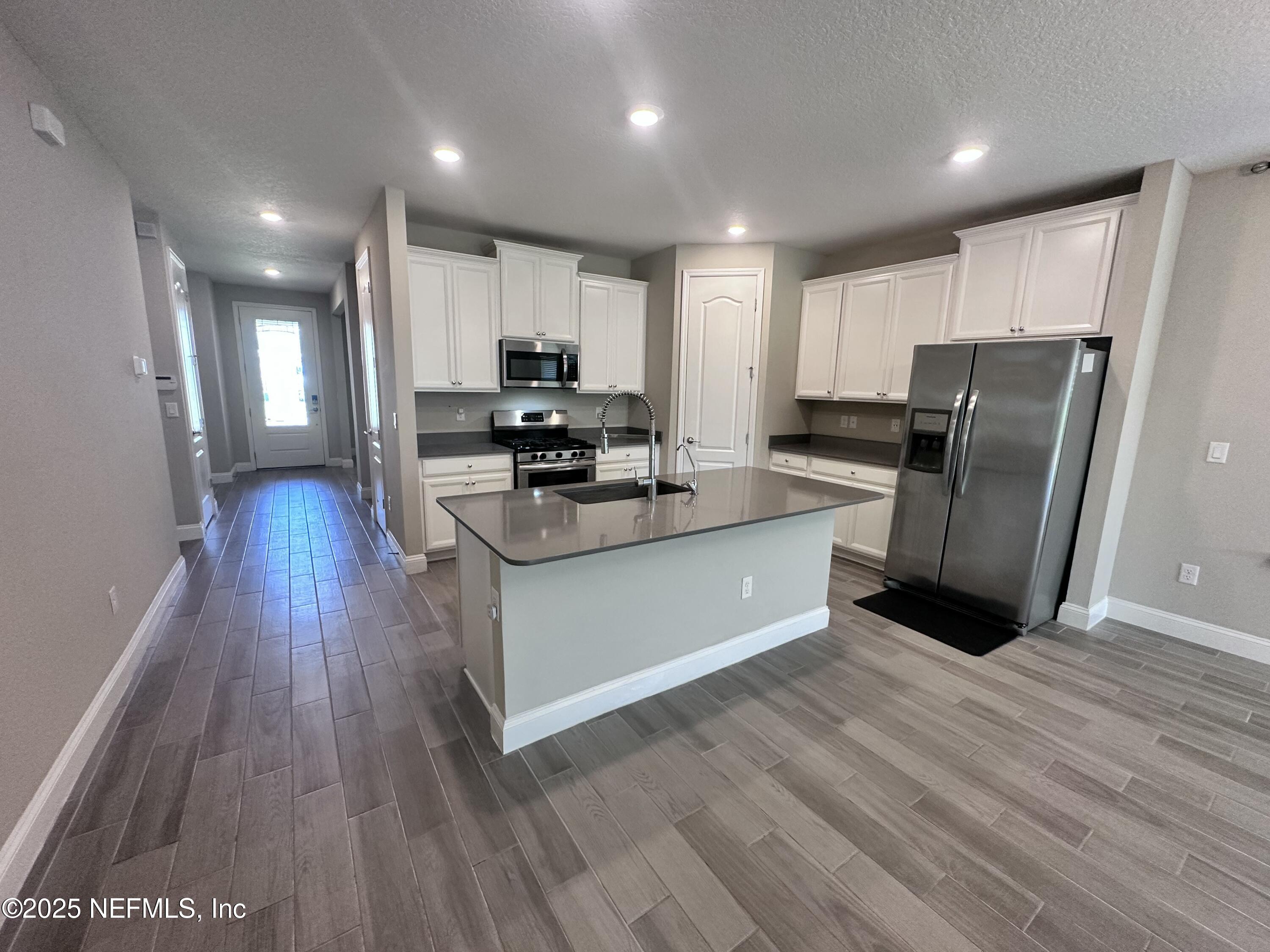 510 Broomsedge Circle St. Augustine, FL 32095 - Photo 8 of 28 a kitchen with stainless steel appliances granite countertop a stove a refrigerator a sink a microwave with wooden floors and cabinets