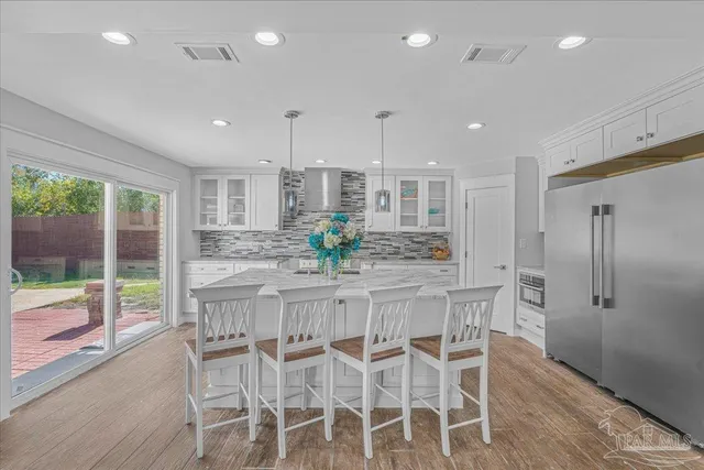a kitchen with stainless steel appliances kitchen island granite countertop a stove and white cabinets