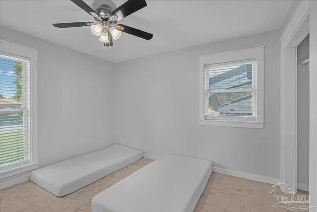 a view of an empty room with a ceiling fan and window