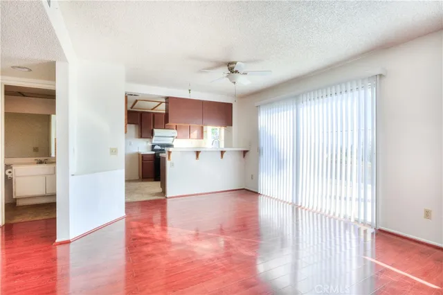 a view of empty room with wooden floor and kitchen view