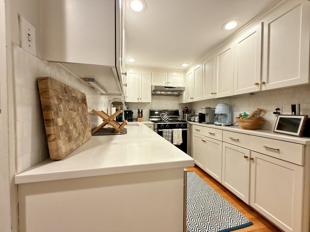 41 Pinckney Street, Unit B Boston, MA 02114 - Photo 17 of 31 a kitchen with stainless steel appliances kitchen island granite countertop a refrigerator a stove and white cabinets with wooden floor