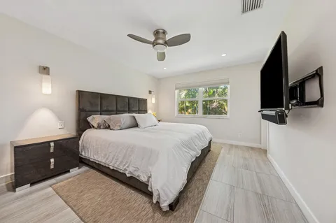 a bedroom with a large bed and a flat tv screen on dresser