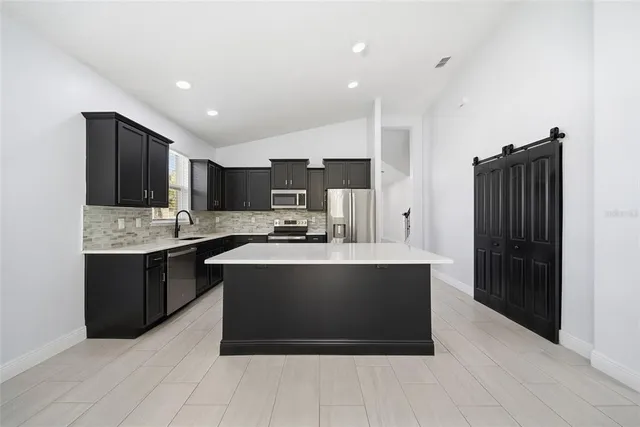 a view of kitchen with stainless steel appliances a stove top oven a refrigerator and cabinets