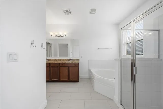 a spacious bathroom with a granite countertop sink a mirror and a bathtub