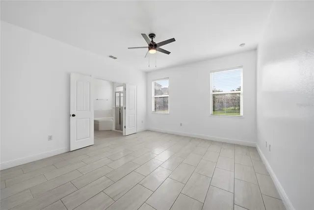 an empty room with a ceiling fan and window