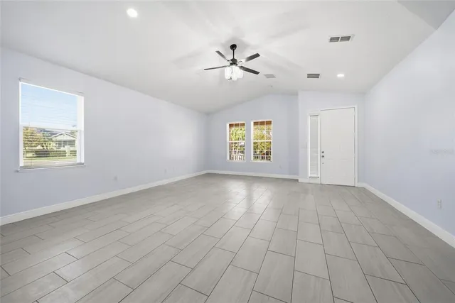an empty room with windows and ceiling fan