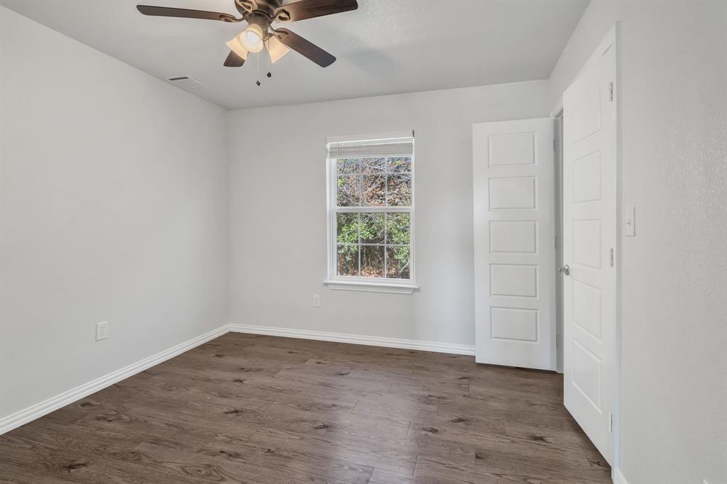 7718 Fm 1886 Azle, TX 76020 - Photo 11 of 16 an empty room with wooden floor chandelier fan and windows