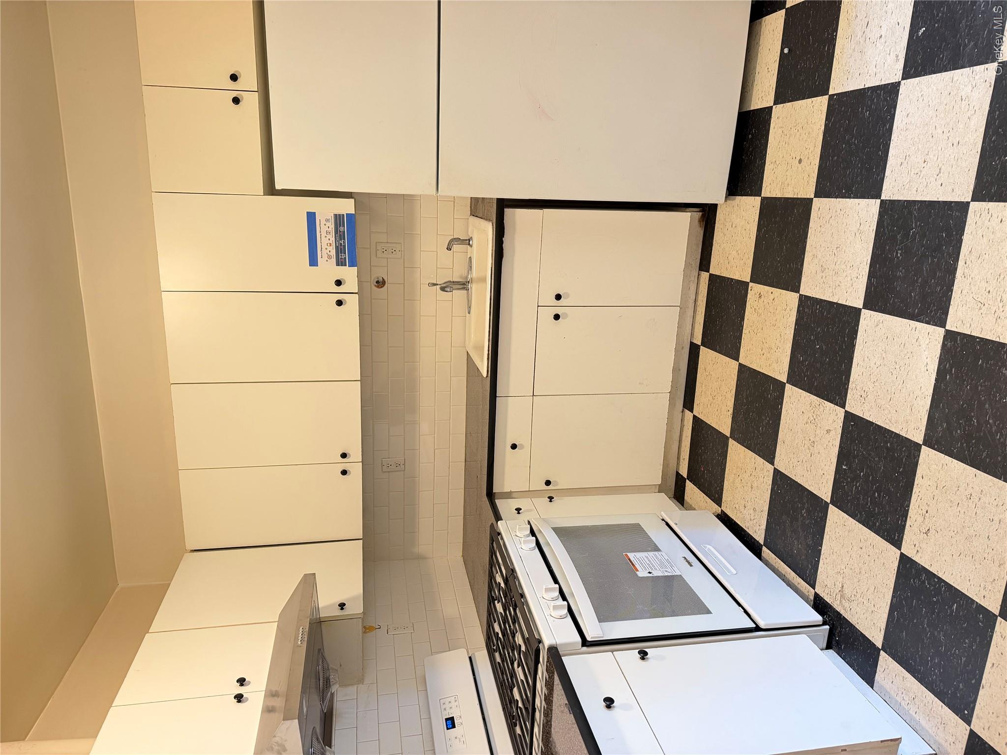 50-05 108th Street Queens, NY 11368 - Photo 4 of 16 a kitchen with a checkered floor and white cabinets