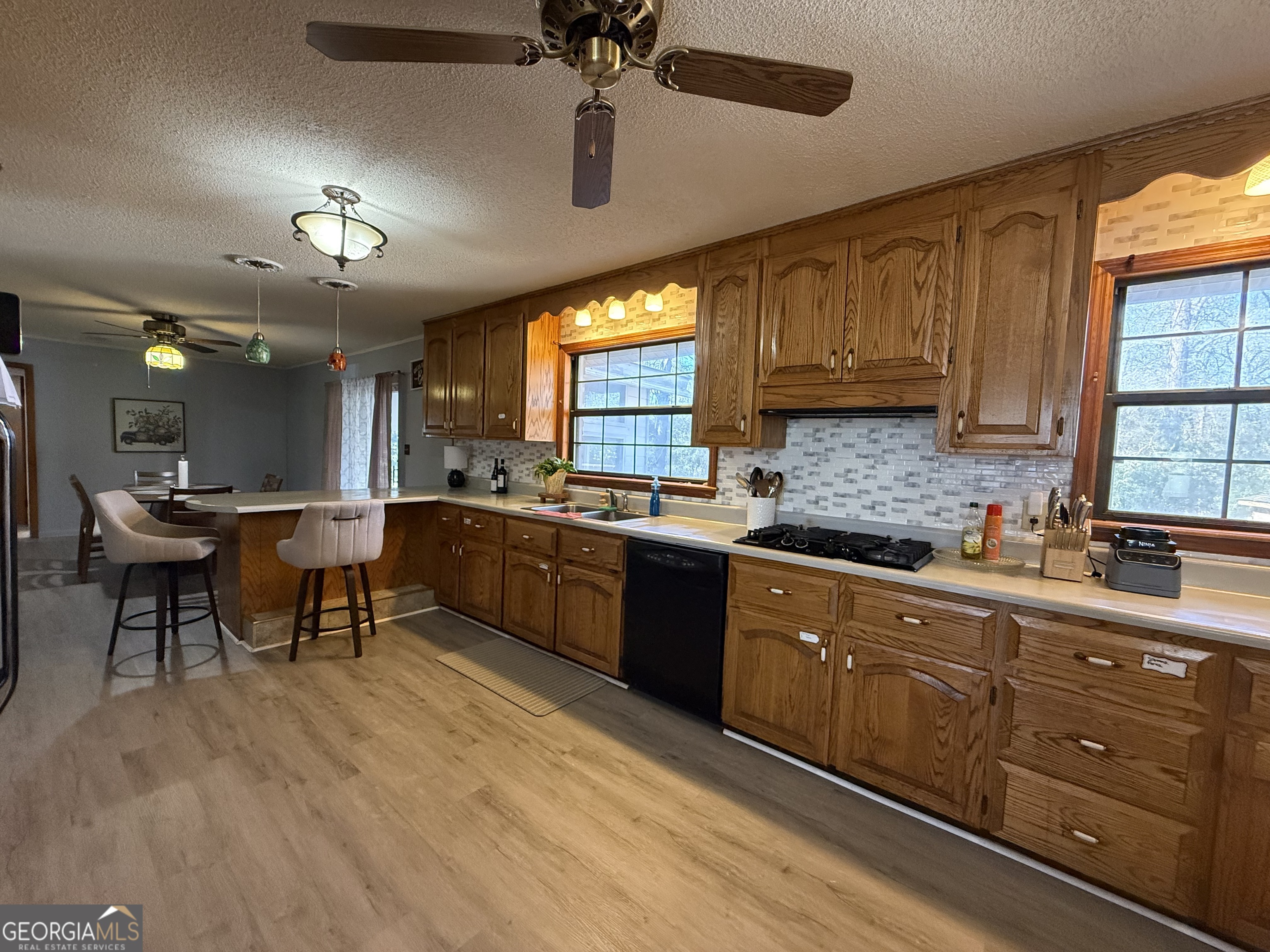 102 Hemlock Street Warner Robins, GA 31093 - Photo 9 of 32 a kitchen with granite countertop a stove a sink a dining table and chairs with wooden floor