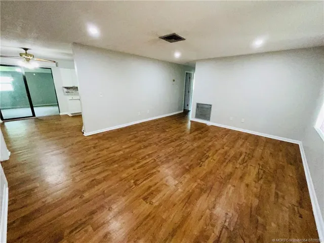 an empty room with wooden floor and a ceiling fan