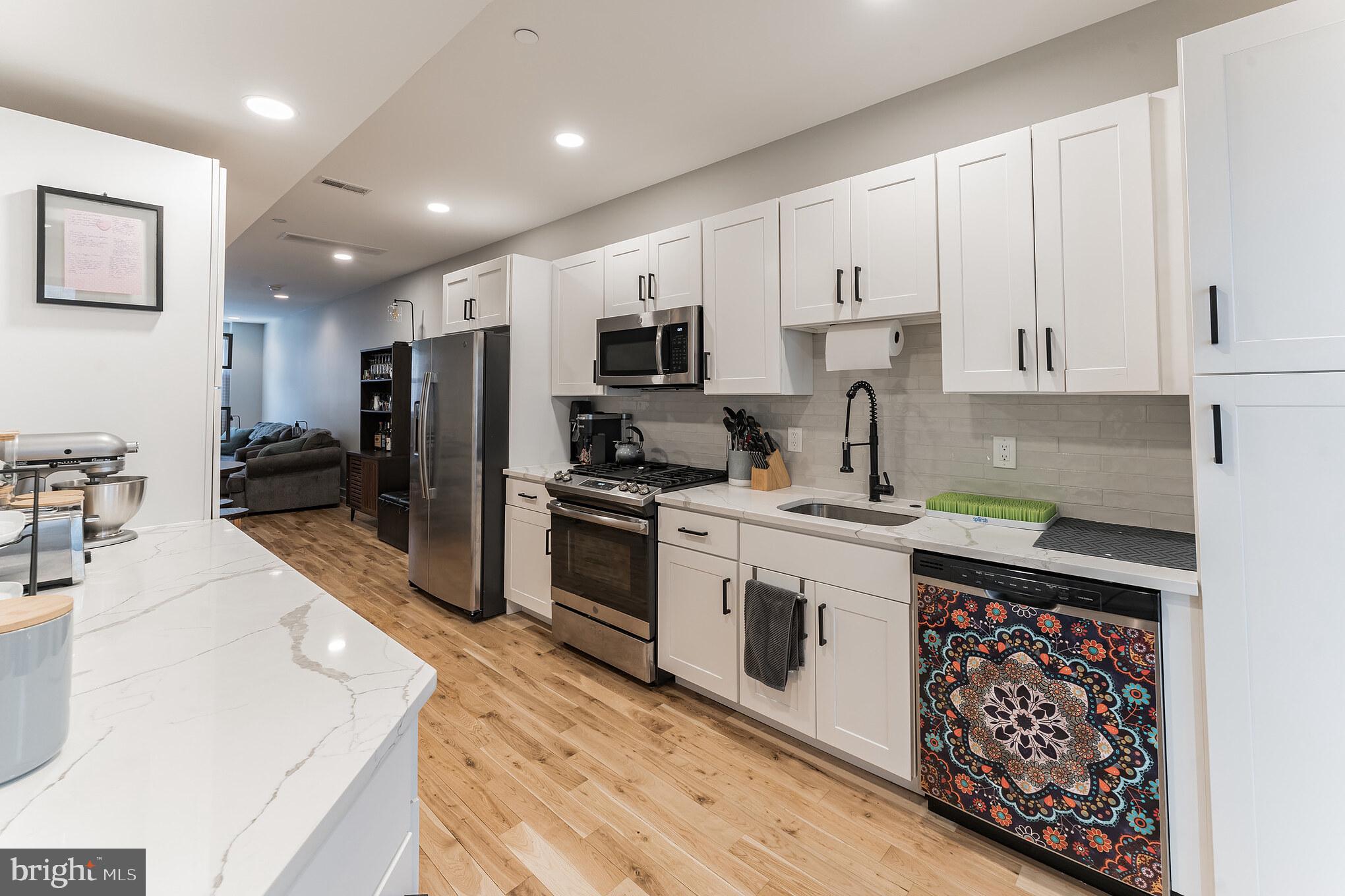 614 Master Street, Unit 1 Philadelphia, PA 19122 - Photo 8 of 28 a kitchen with stainless steel appliances granite countertop a stove top oven a sink a refrigerator white cabinets and wooden floor