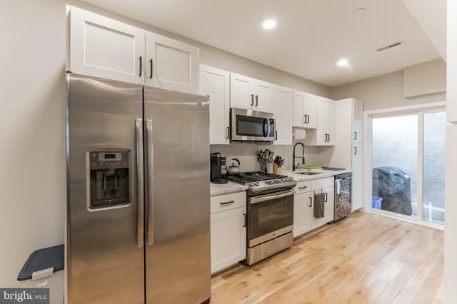 a kitchen with cabinets stainless steel appliances and wooden floor