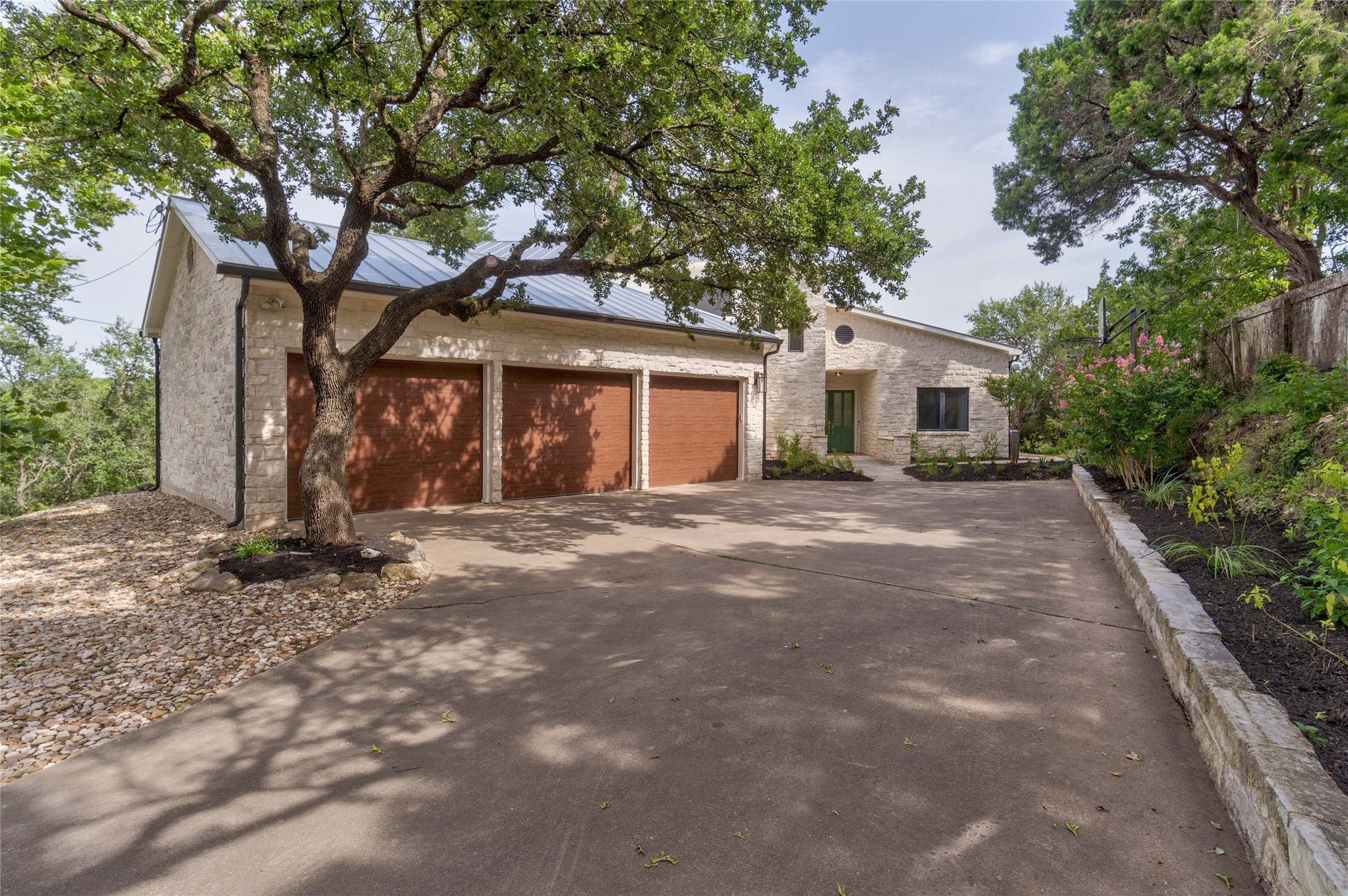 2102 Paisano Road Austin, TX 78746 - Photo 3 of 26 View of front of property featuring concrete driveway and stone siding