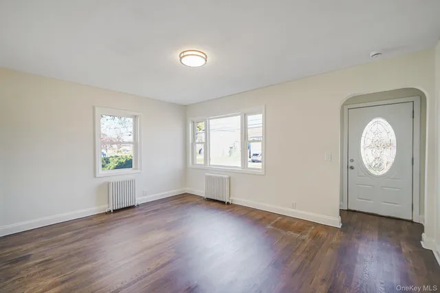 an empty room with wooden floor and window