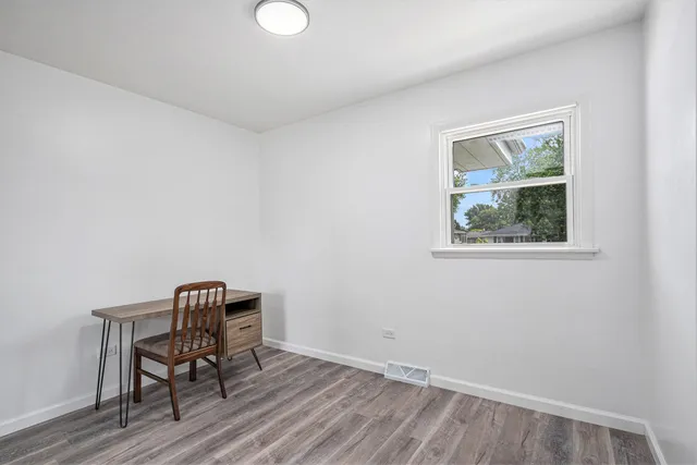 a view of workspace room with wooden floor lounge chair and windows