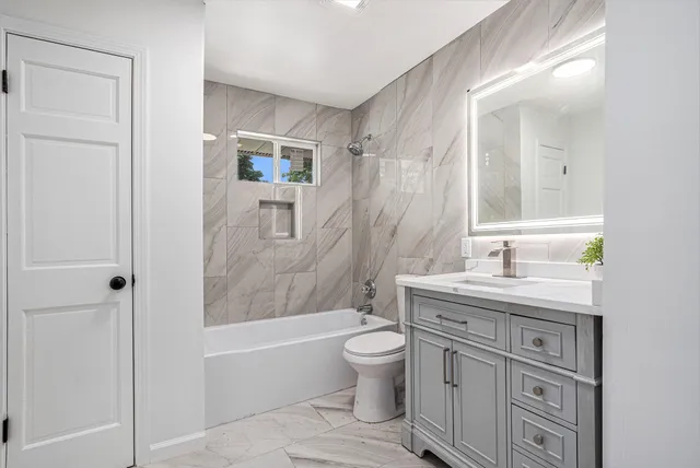 a bathroom with a granite countertop sink a toilet and shower